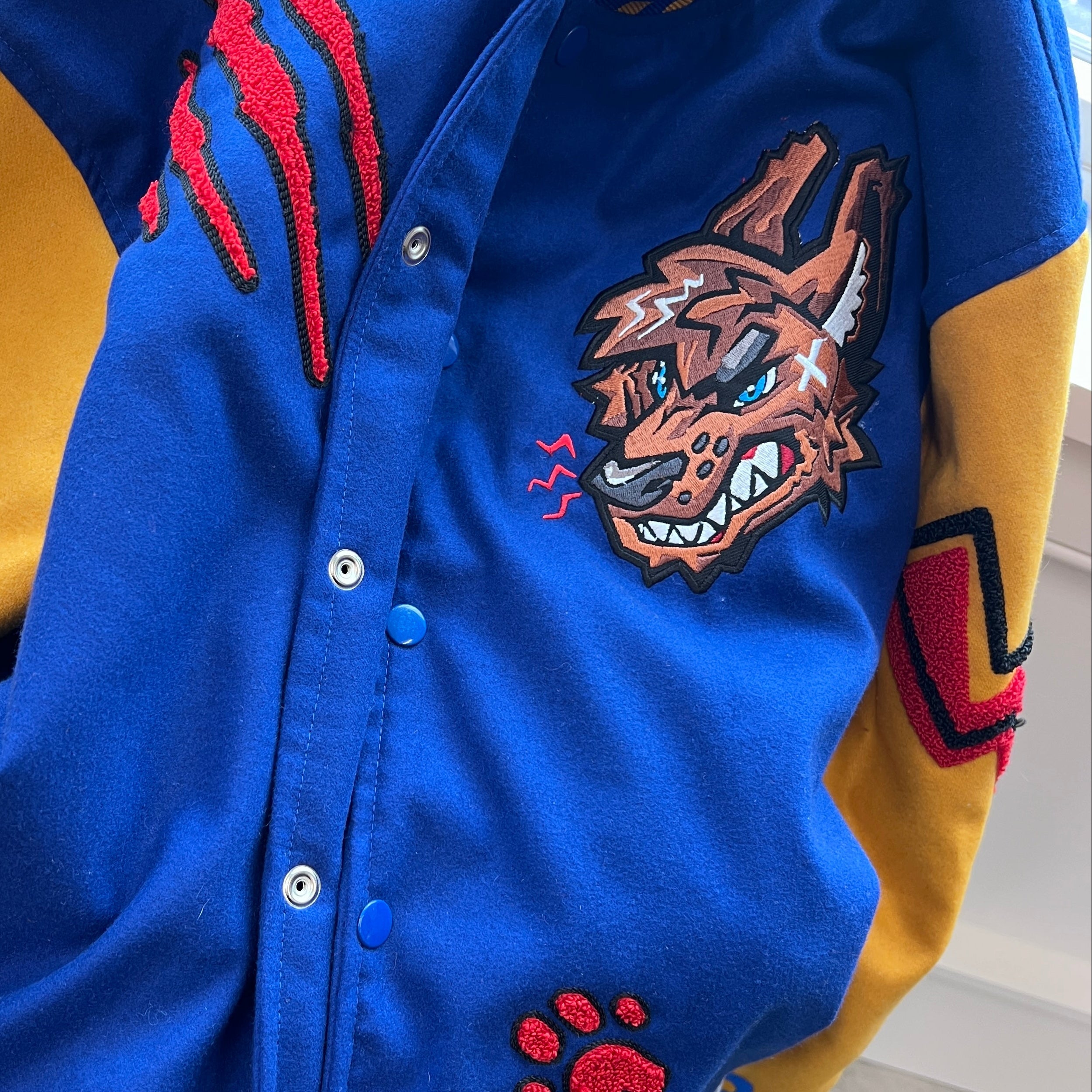Blue and yellow jacket with red wolf design and paw prints on a neutral background